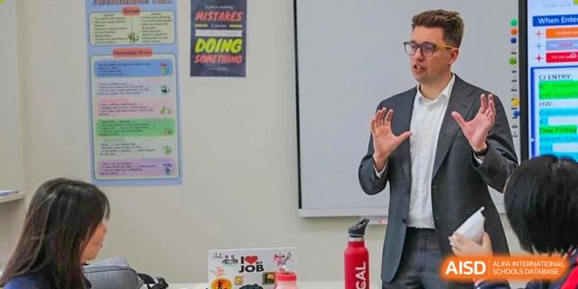 A close-up of a teacher leading a discussion in a bright, modern classroom focused on student engagement at BASIS International School Wuhan.