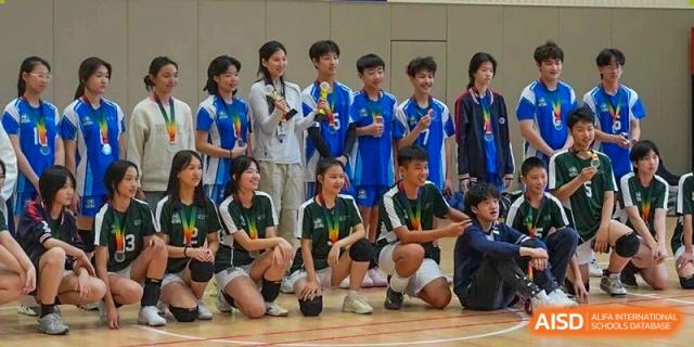 A school sports team in blue and green uniforms poses together with a trophy on the court at BASIS International School Wuhan.