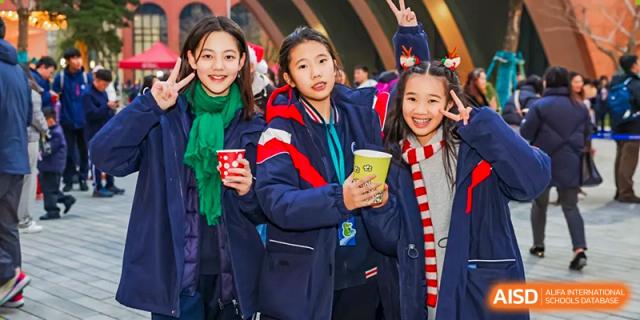 Students in navy and red jackets holding colorful paper cups during an outdoor school event at BASIS International School Wuhan.