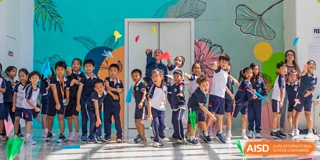 Young students in school uniforms playfully throwing colorful paper airplanes in a hallway at BASIS International School Wuhan.