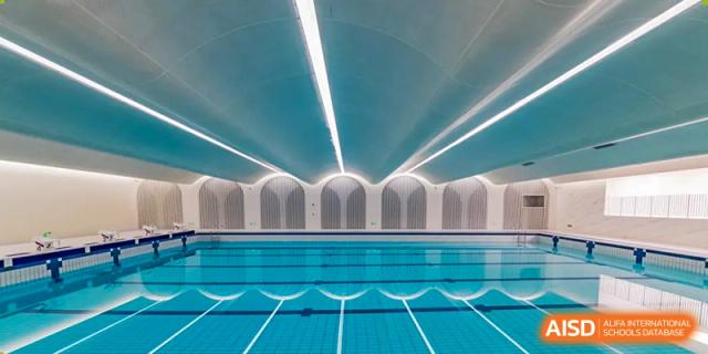 A wide shot of a pristine, professional indoor swimming pool with modern architecture at BASIS International School Wuhan.