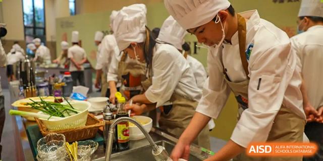 Students wearing chef hats and aprons learning culinary skills and food preparation in a kitchen at BASIS International School Wuhan.