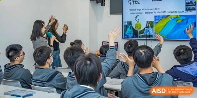 Engaged students from Hangzhou Entel Foreign Language School raising their hands enthusiastically to answer a question or participate in a classroom discussion.