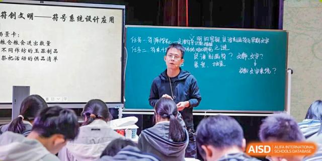 A student presentation in a classroom at Hangzhou Entel Foreign Language School. The student stands before a chalkboard addressing classmates seated in the foreground.