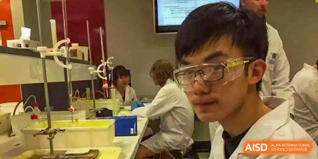 Students wearing safety goggles conduct a lab experiment in a science room at Hangzhou Entel Foreign Language School. The photo is taken from a close-up perspective of one student.