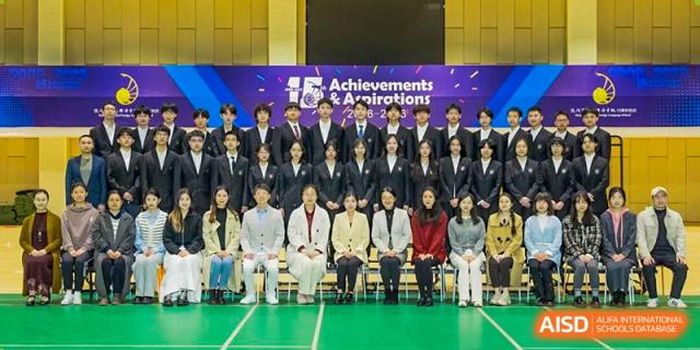 A large group photo of students and possibly faculty seated and standing together on a stage with a banner that reads "Achievements & Aspirations" at Hangzhou Entel Foreign Language School.