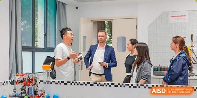 A group of people, including two men and two women, having a discussion in a bright, modern interior space at Hangzhou Entel Foreign Language School.