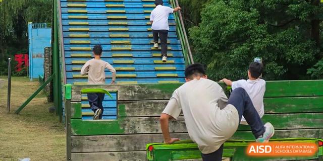 Students climb a set of stairs or bleachers during a physical activity or race on campus grounds at Hangzhou Entel Foreign Language School.