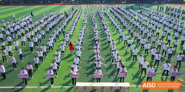 Mass exercise at Hangzhou Entel Foreign Language School with students in formation. Large group physical education drill at a school sports event.