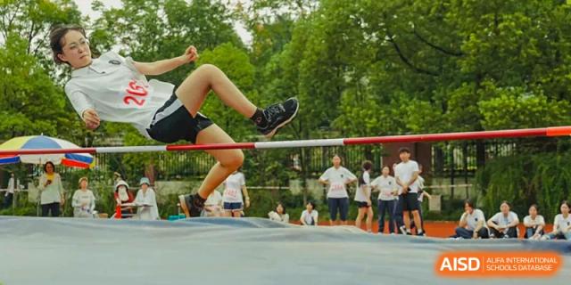 A student performing a high jump over the bar at Hangzhou Entel Foreign Language School's track and field event. Track and field competition.