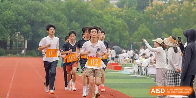 Students of Hangzhou Entel Foreign Language School competing in a long-distance running event on a green field during the school's annual outdoor sports day.
