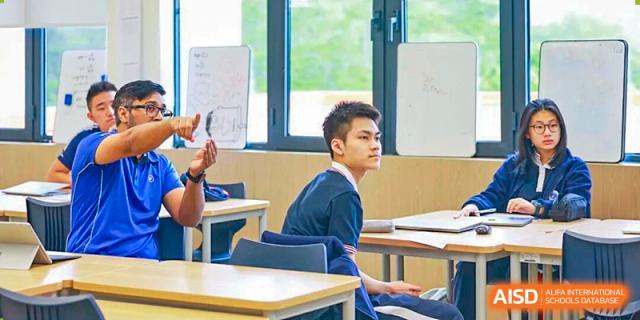 A focused student in a blue school uniform sits at his desk in a bright classroom at BASIS International School Park Lane Harbour.