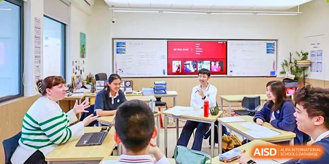 Students and a teacher sit around a table for a small group discussion or seminar session at BASIS International School Park Lane Harbour.