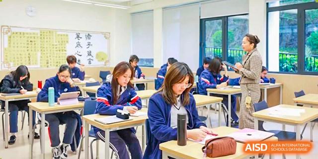 A female student in uniform works attentively at her desk, with a small electronic device nearby at BASIS International School Park Lane Harbour.