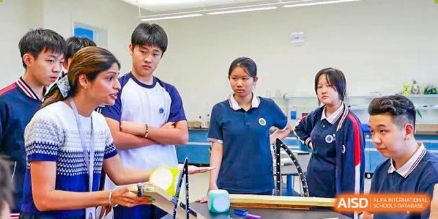 Two high school students in navy and white uniforms look intently at a science experiment on a lab bench at BASIS International School Park Lane Harbour.
