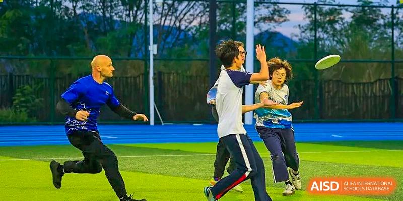 Students are playing Ultimate Frisbee on a green outdoor field, with one preparing to throw the disc at BASIS International School Park Lane Harbour.