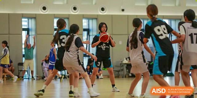 Female students are competing in an indoor sport, possibly handball or dodgeball, during a game at BASIS International School Park Lane Harbour.