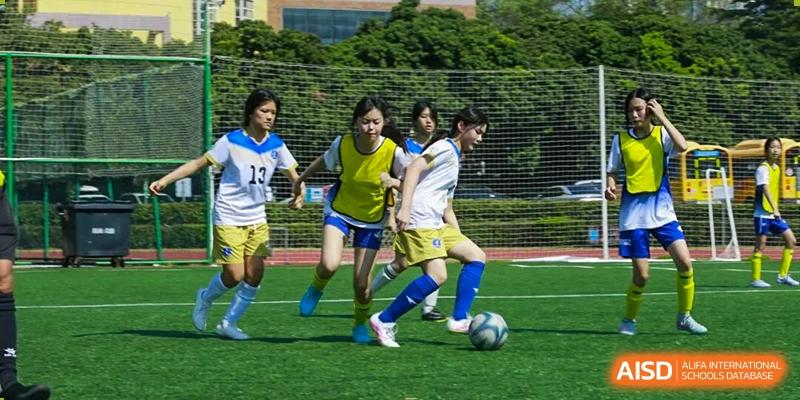 Female students are playing soccer on a grass field, focused on dribbling the ball during a practice at BASIS International School Park Lane Harbour.