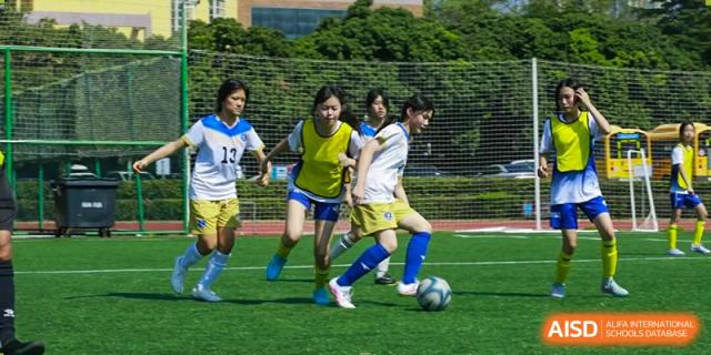 Female students are playing soccer on a grass field, focused on dribbling the ball during a practice at BASIS International School Park Lane Harbour.