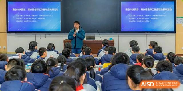 A person speaking into a microphone while standing in front of a class full of students taking notes in a large classroom at Nanjing Foreign Language School.