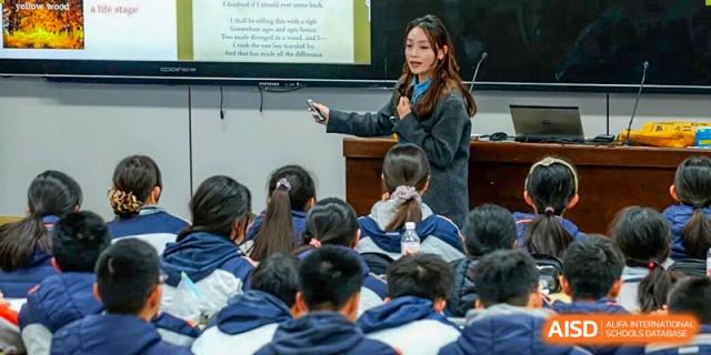 A female teacher using a pointer to present information on a screen to a classroom full of attentive students at Nanjing Foreign Language School.