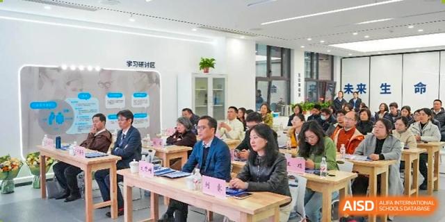 Adults and students are sitting around a conference table in a modern, well-lit meeting room having a focused discussion, typical of events at Nanjing Foreign Language School.