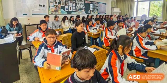 Students are actively engaged in reading or classwork in a packed classroom setting, focusing intently on their materials, a common scene at Nanjing Foreign Language School.