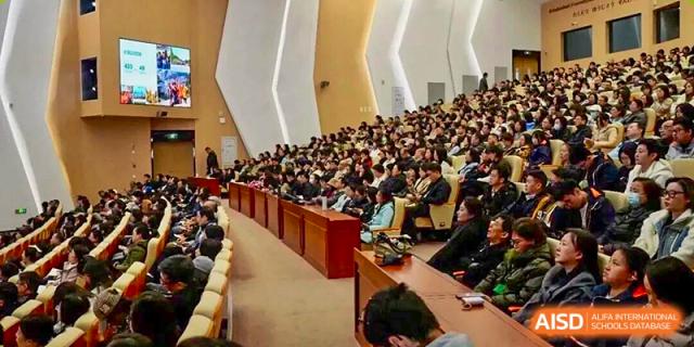 A very large audience seated closely in a wooden auditorium, looking towards the front during a meeting or assembly at Nanjing Foreign Language School.