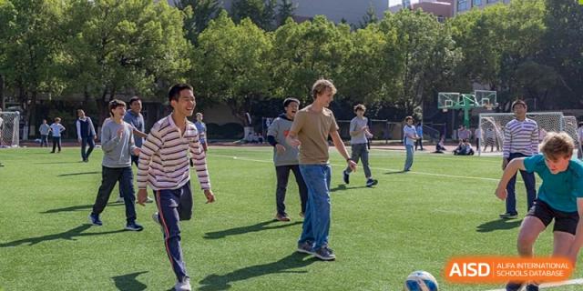 A group of students casually enjoying an outdoor activity on a sunny grassy sports field at Nanjing Foreign Language School.