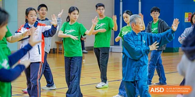 A group of students in green shirts standing and interacting indoors, possibly during a physical activity or game at Nanjing Foreign Language School.