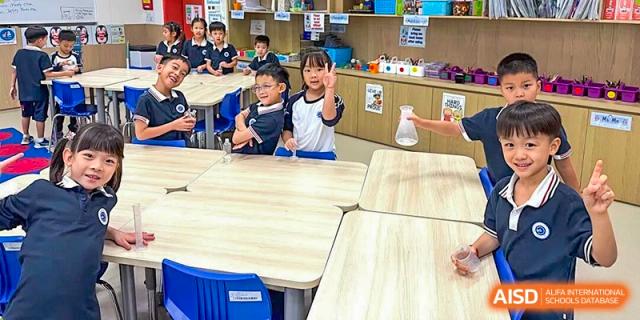 Young primary students gather around a classroom table to observe a science experiment involving a glass flask at BASIS International School Shenzhen.