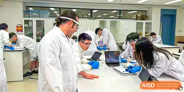 Students and a teacher wearing protective gear work together on a complex science project in the lab at BASIS International School Shenzhen.