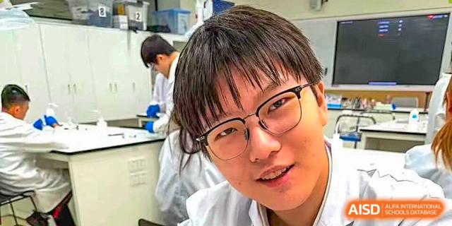 A close-up portrait of a student wearing glasses and a white lab coat during a science practical at BASIS International School Shenzhen.