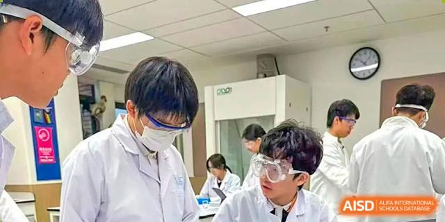 Science students wearing face masks and safety goggles conduct an experiment in a modern laboratory at BASIS International School Shenzhen.