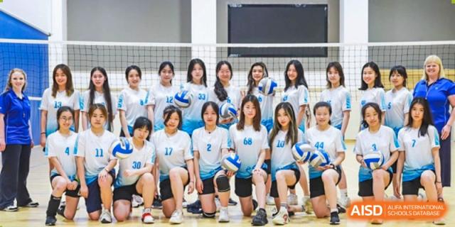 The girls' volleyball team poses together in their blue and white uniforms on an indoor court at BASIS International School Shenzhen.