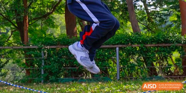 A close-up action shot of a student’s feet mid-air while jumping during an outdoor sports activity at BASIS International School Shenzhen.