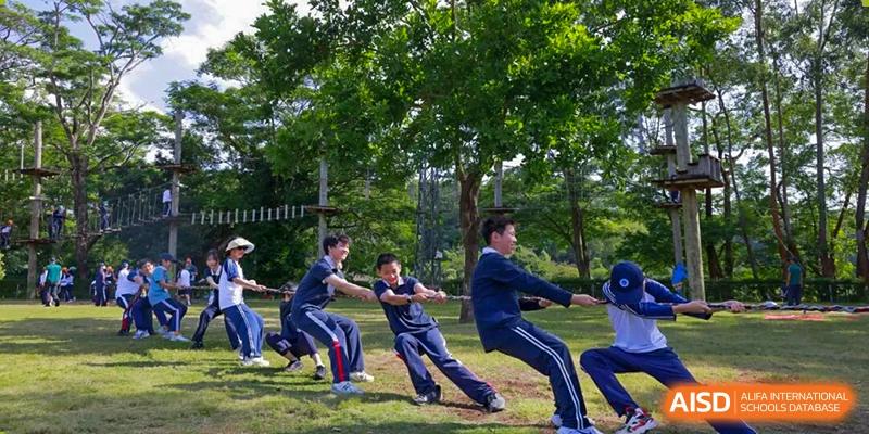 A group of students pulls a rope during a competitive game of tug-of-war on the grass at BASIS International School Shenzhen.