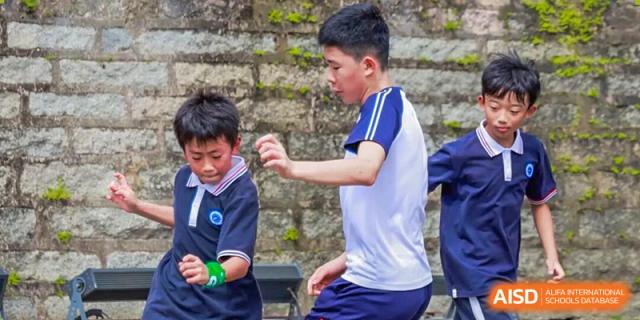 Two young boys in physical education uniforms participate in an active outdoor exercise at BASIS International School Shenzhen.
