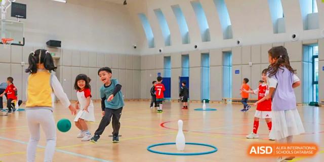 A young student cheers while playing an indoor bowling game in a bright gymnasium at BASIS International School Shenzhen.