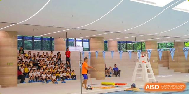 A staff member prepares equipment near the indoor swimming pool area during a school event at BASIS International School Shenzhen.