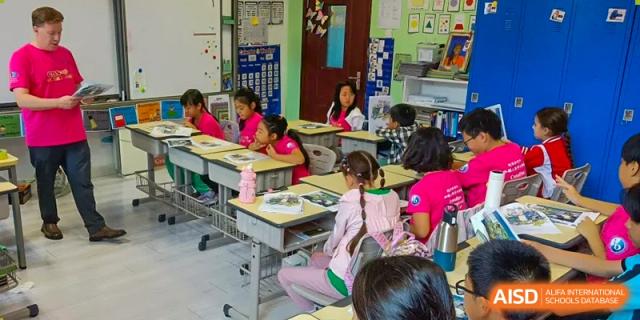 Young students in pink and purple shirts sit attentively at their desks during a primary school lesson at the Canadian International School of Shenyang.