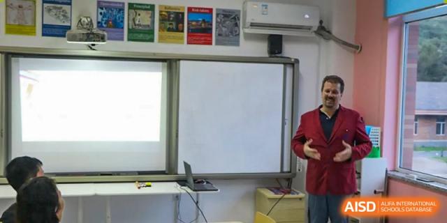 A classroom setup features a large interactive whiteboard and a laptop ready for a digital presentation at the Canadian International School of Shenyang.