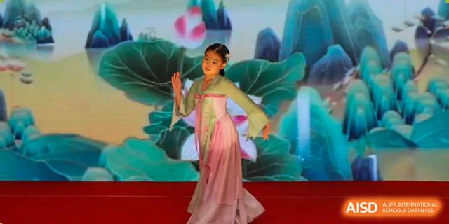 A student performs a traditional dance in an elegant pink costume in front of a lotus-themed backdrop at the Canadian International School of Shenyang.