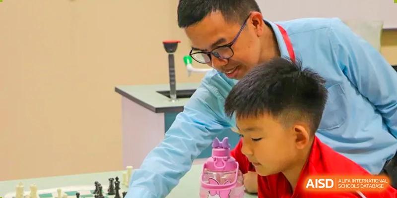 A teacher assists a young student with a hands-on classroom project involving colorful materials at the Canadian International School of Shenyang.