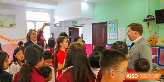 A group of young students in red uniforms stands in a bright school hallway during an event at the Canadian International School of Shenyang.