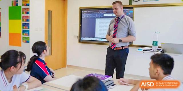 A male teacher giving a presentation in a modern classroom with a smart board, instructing students during an interactive lesson at Concordia International School Ningbo.