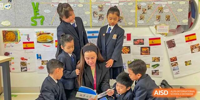A female teacher reading a book to a group of young students in uniform in a classroom, promoting literacy and group learning at Concordia International School Ningbo.