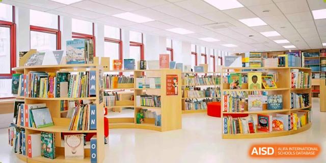 A bright, well-stocked school library with many bookshelves and natural light, providing a vibrant reading environment at Concordia International School Ningbo.