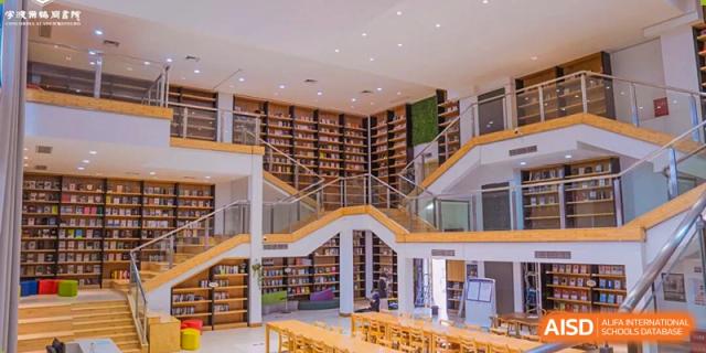 A spacious, multi-story library interior with long rows of bookshelves and staircases, featuring extensive resources and grand architecture at Concordia International School Ningbo.