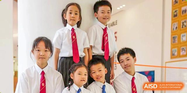 A group of students in white shirts and red ties, featuring smiling younger and older children in school uniform together at Concordia International School Ningbo.